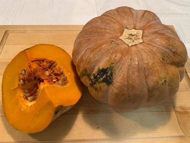 A close up of two pumpkins on a cutting board